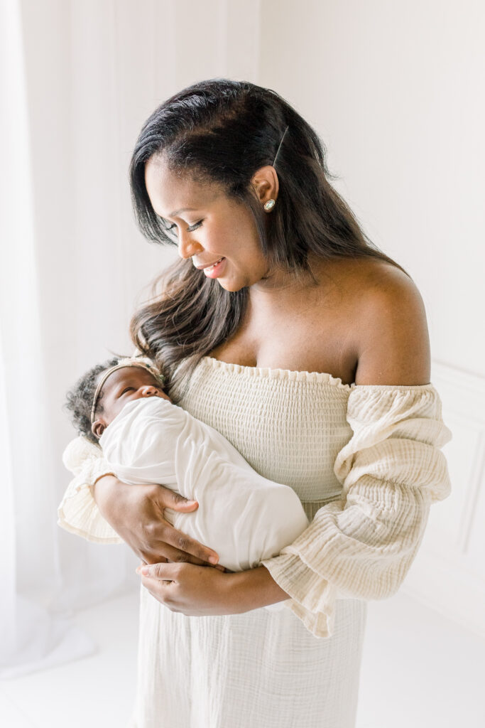 Mississippi Newborn photographer captures image of mom hold baby in white studio for newborn session. 