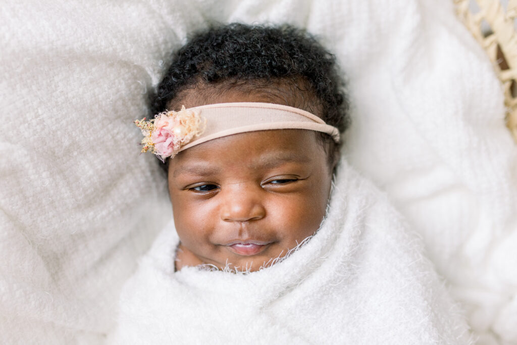 Newborn baby girl swaddled in white fabric in moses basket for Newborn session by Mississippi Newborn Photographer.