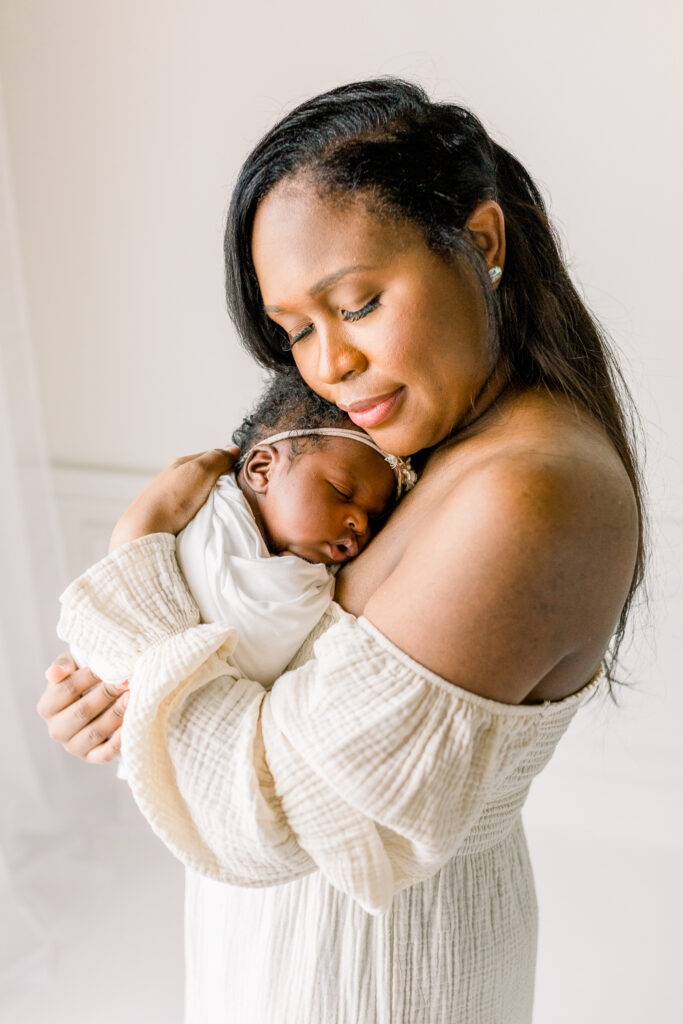 Mom cuddling newborn baby girl in white studio by Mississippi Newborn Photographer. 