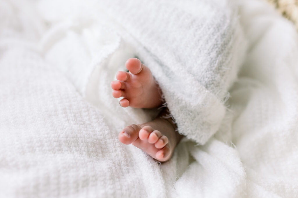 Newborn baby girl swaddled in white fabric. Close up of baby toes peeping out by Mississippi Newborn Photographer.