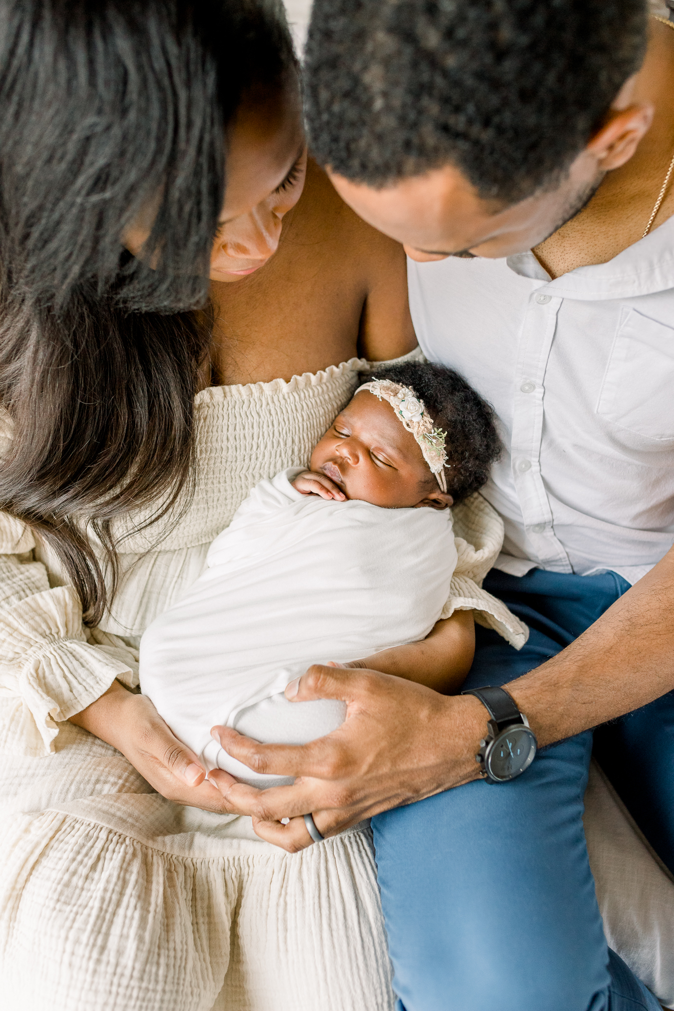 Mississippi Newborn Photographer in studio newborn session. Mom and dad holding swaddled baby girl in white studio with natural light.