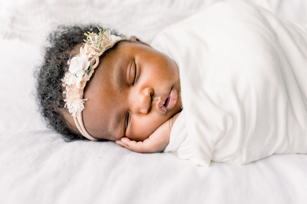 Close up of newborn baby girl swaddled n white on white bed in natural light studio by Mississippi newborn Photographer.