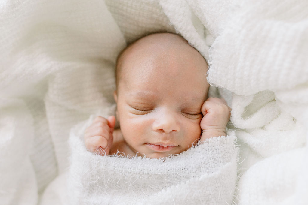 Baby boy swaddled in white in Moses basket for newborn studio session at CJ and Olive Photography's studio. 