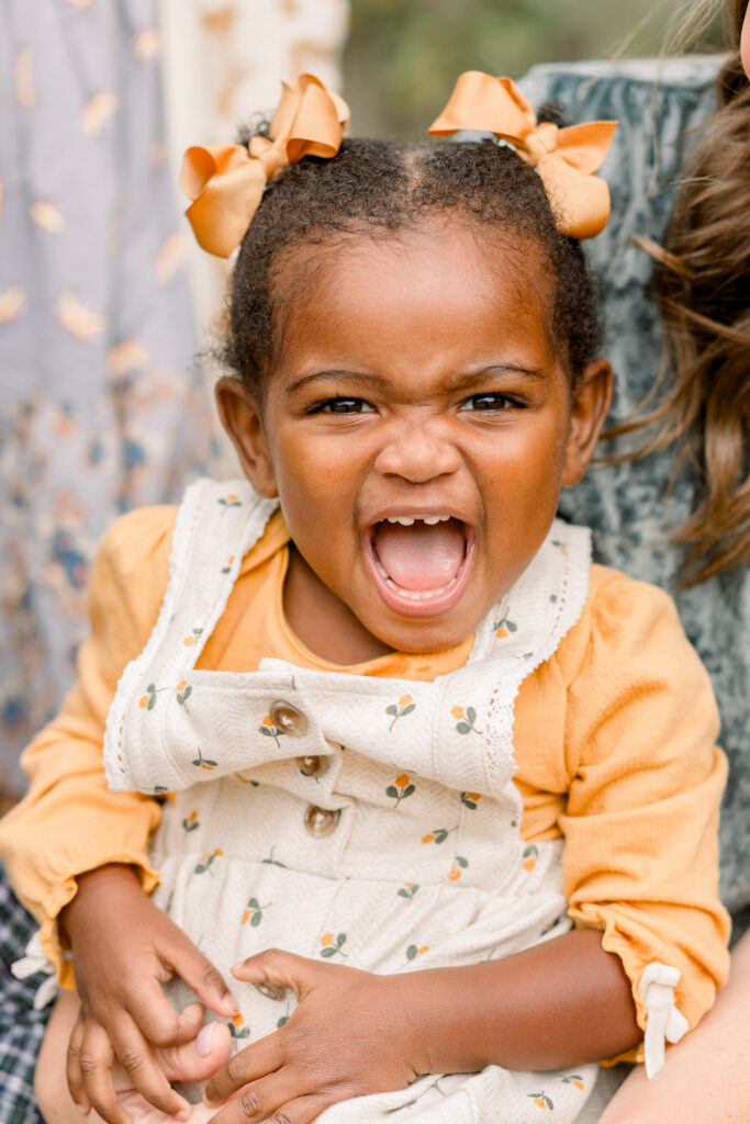 Little girl with pigtails smiling big at camera for fall family photos by Mississippi Family Photographer. 