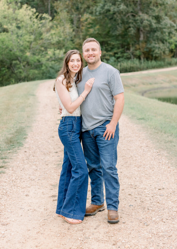 Couple poses together on dirt road and smiles at camera for fall family photos. Photograph taken by Brandon Family Photographer, CJ and Olive Photography. 