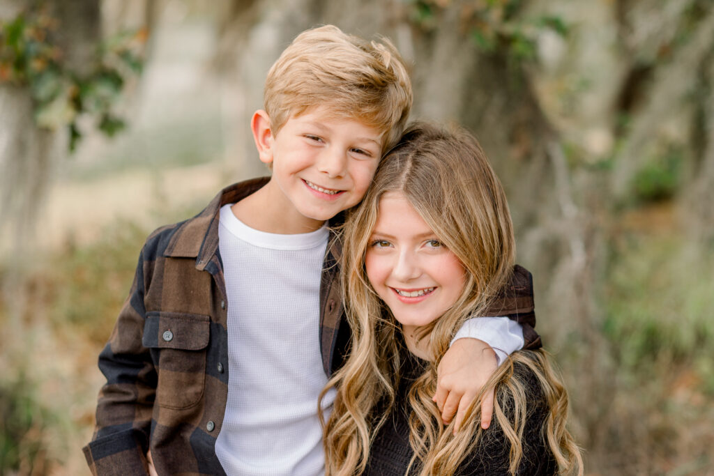 Sister and brother smile at camera for fall family photos by Flora, Mississippi family photographer. 