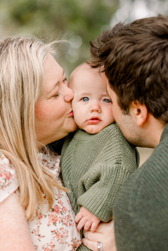 Mom and dad kiss baby boy's cheek for fall family photos by Madison family photographer. 