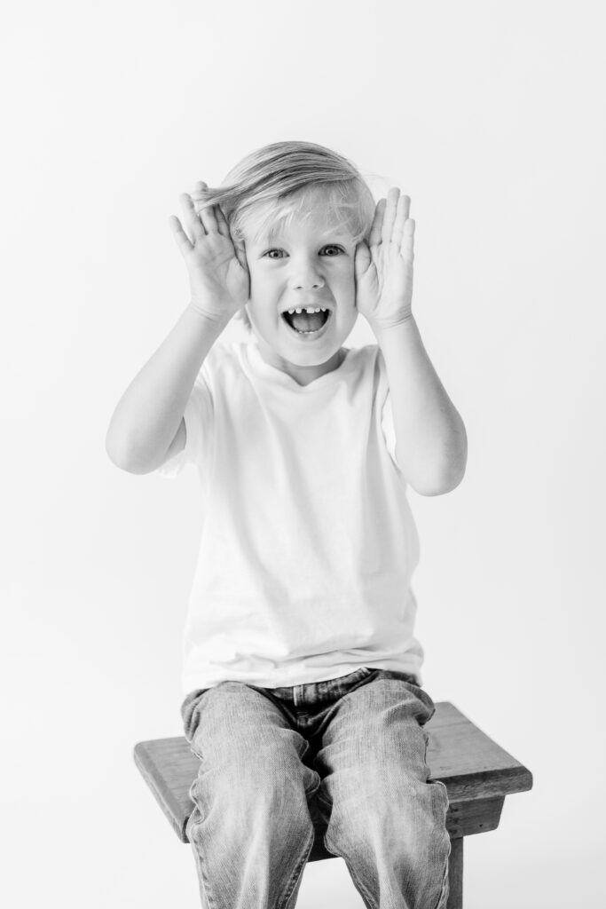 Little boy plays peek a boo for in studio session by CJ and Olive Photography, a Brandon Family Photographer.